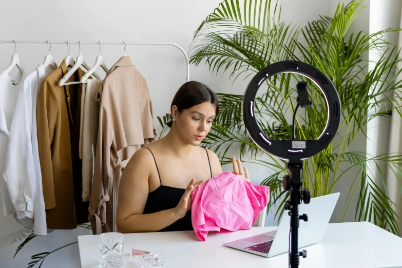 a woman in a black top is working on a laptop while wearing a pink bag