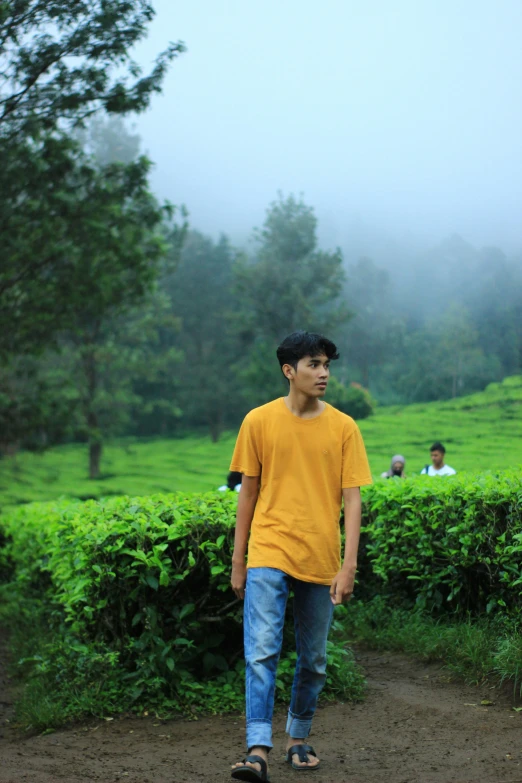 a young man walks on the side of a path, as other people sit in the background