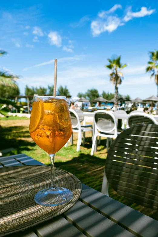 a glass of drink is sitting on a table outdoors