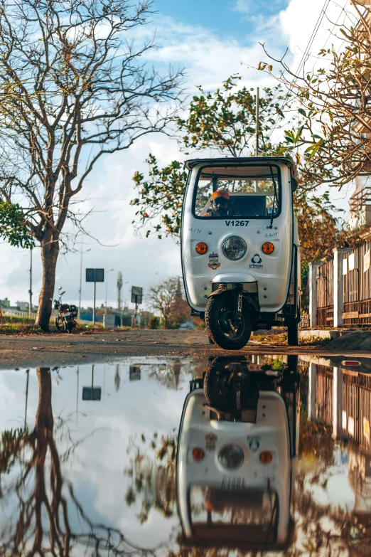 a tiny white car is reflected in the wet street