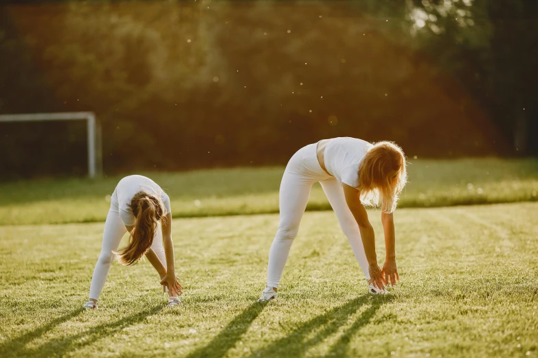 two woman in white shirts leaning over on their knees