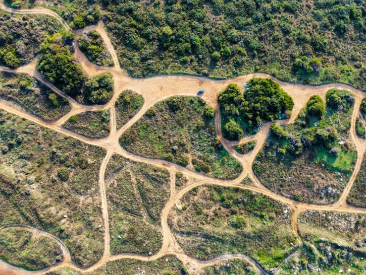 an aerial view of a dirt road in the middle of an area with trees