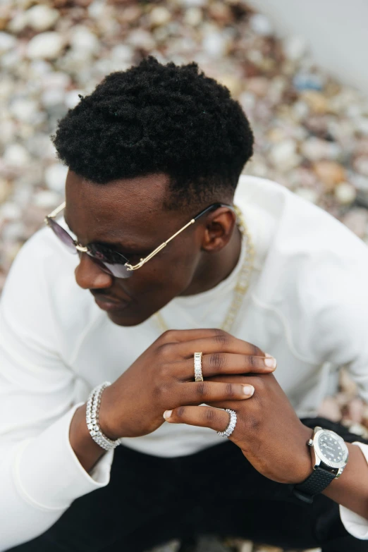 a man with a celet, glasses and ring is looking at his watch