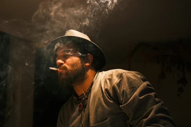 a bearded man is sitting down smoking a cigarette