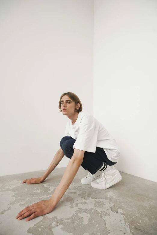 a young man crouched down looking down in the corner