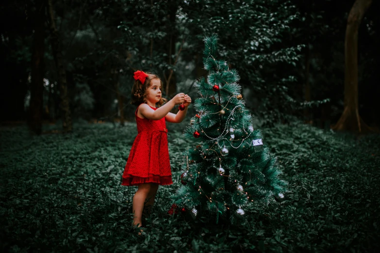 little girl in red dress painting christmas tree