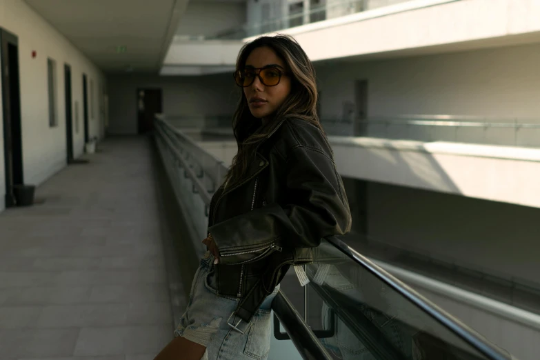 a young woman posing while standing near a fence