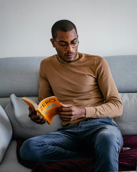 the man is reading the book on the couch