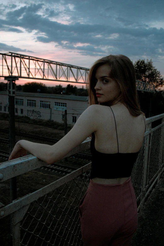 the back end of a girl standing at the top of a bridge