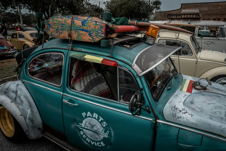 a turquoise old car with some surfboards on top of it