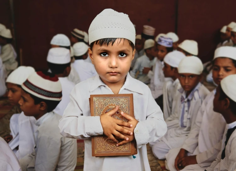 a boy wearing a hat holding a book