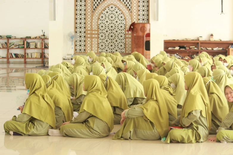 many women dressed in green shawls sitting on the floor