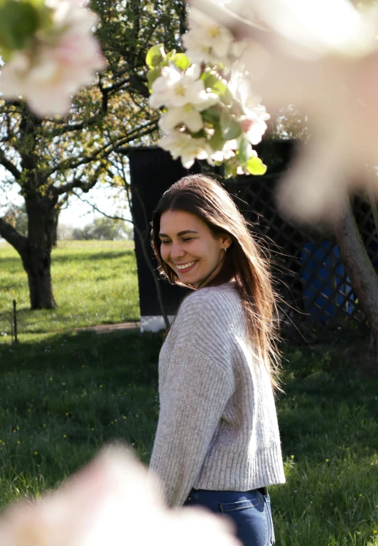 a young woman stands in the sun under flowering trees