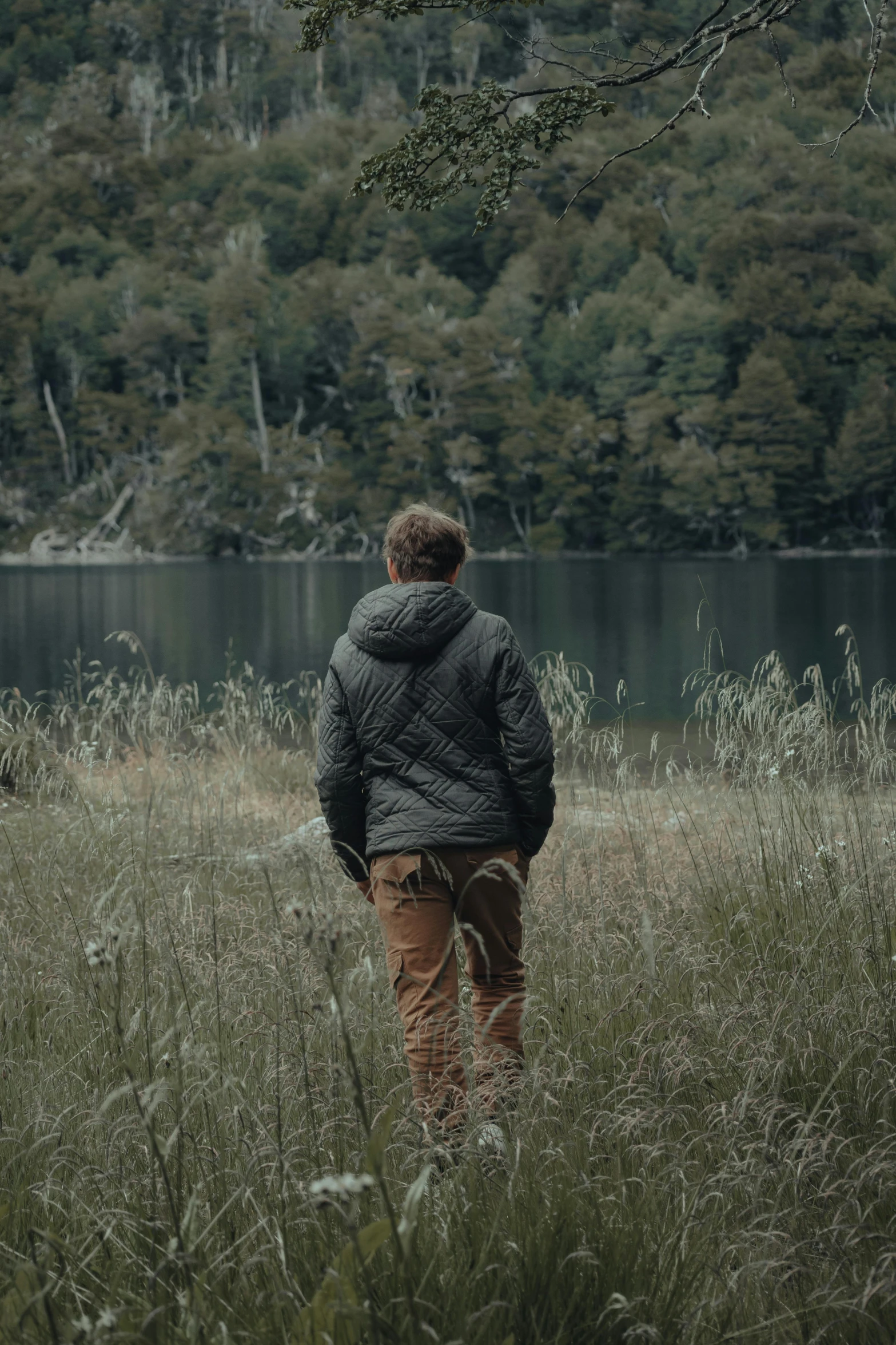 the person is standing by the lake with his back to the camera