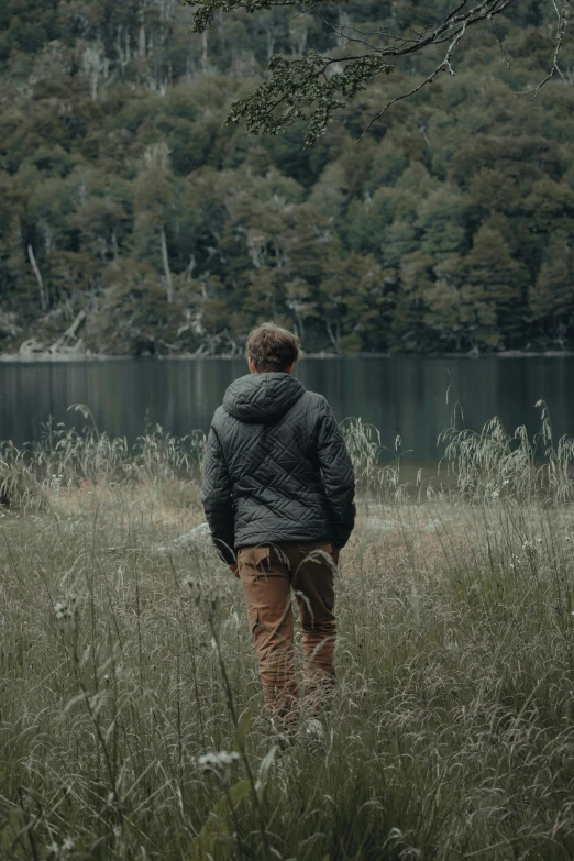 the person is standing by the lake with his back to the camera