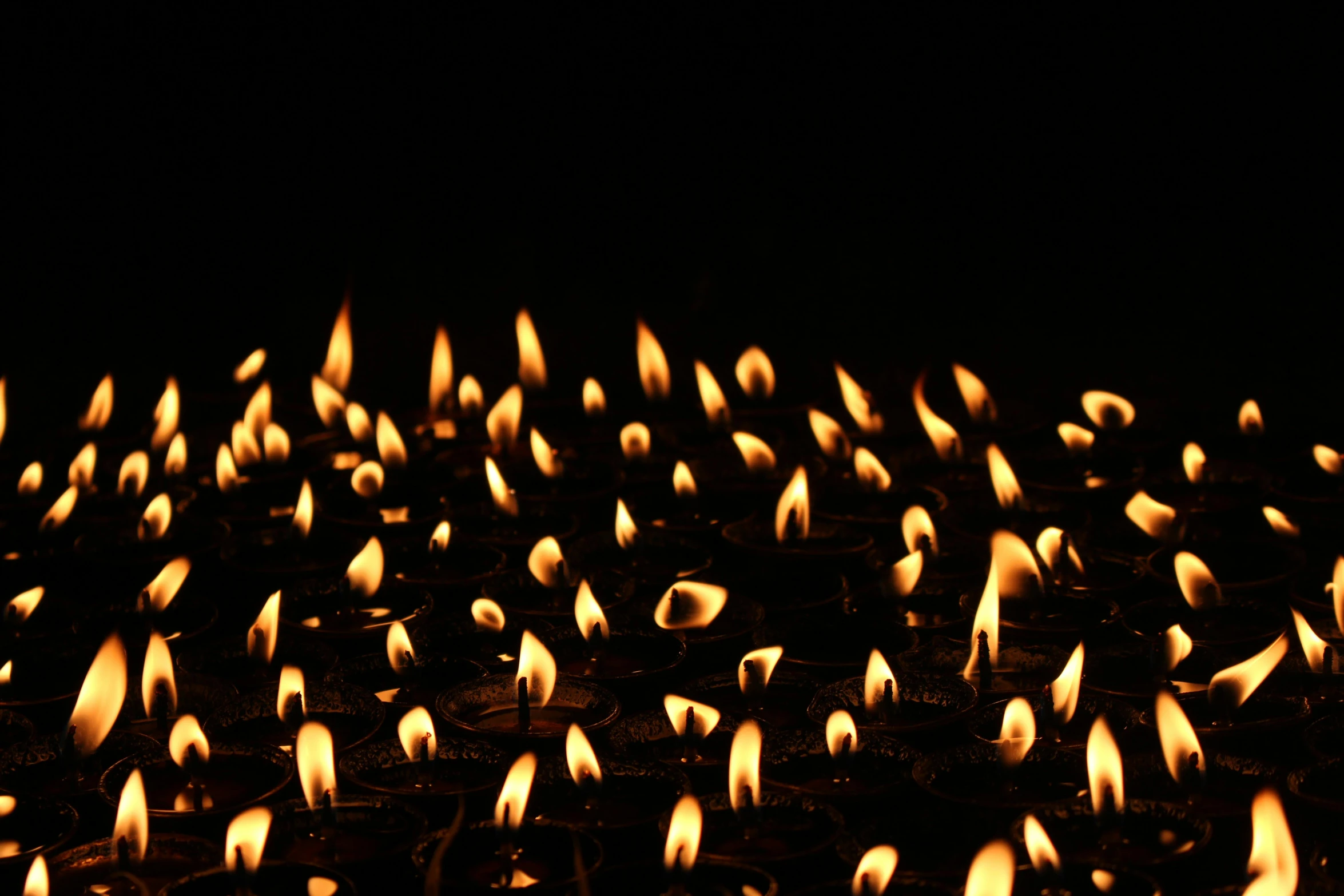 lit candles floating in the dark with black background