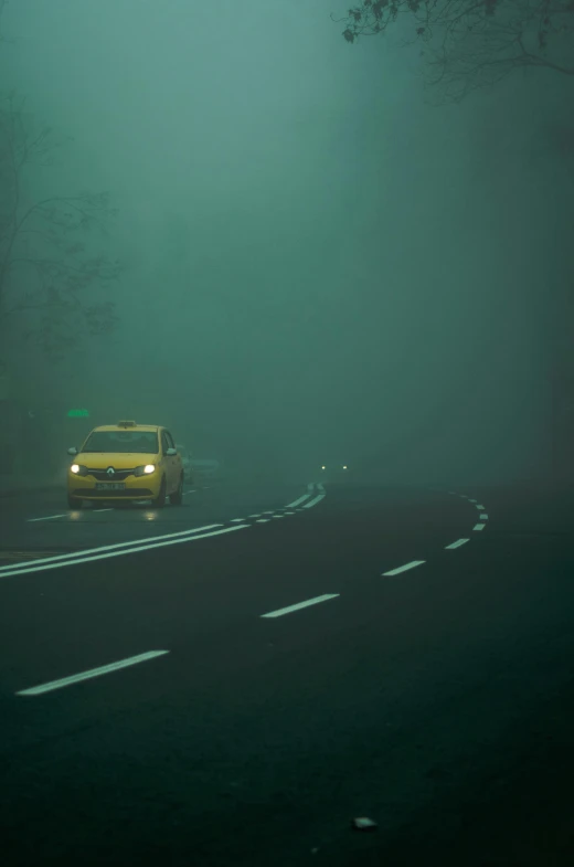 a yellow car driving in the rain on a road