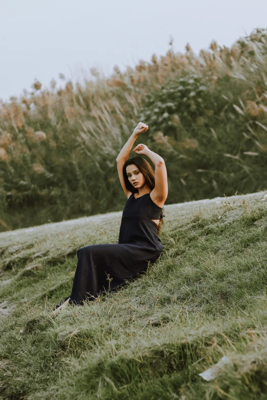 a woman sitting on top of a grassy hill holding up a red kite