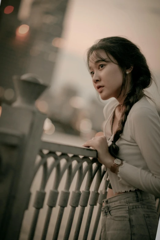 the girl is posing by a railing and looking at the camera