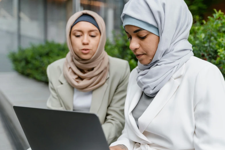 two women with headscarves are looking at their computer