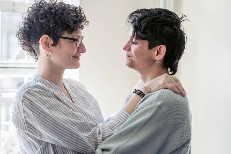 two women smile and hold each other in a room