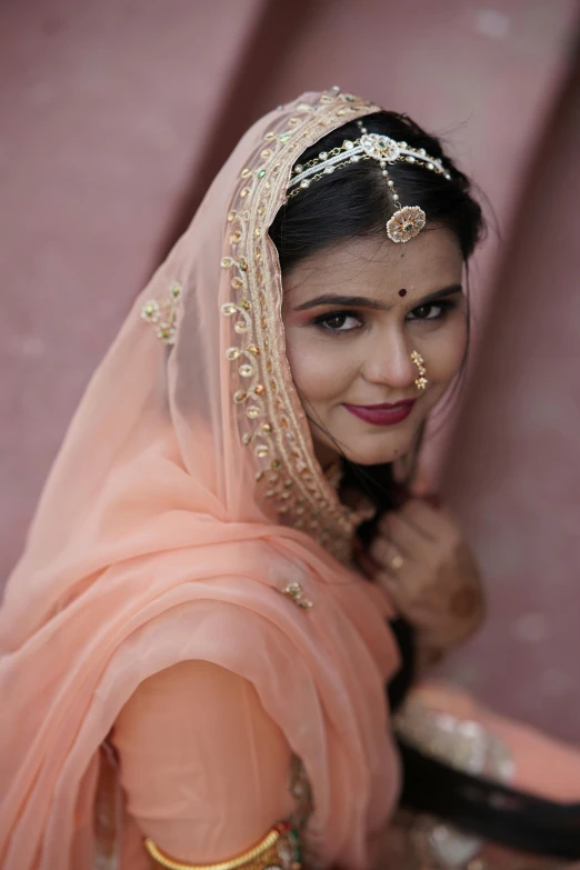 a woman wearing a pink veil poses for the camera