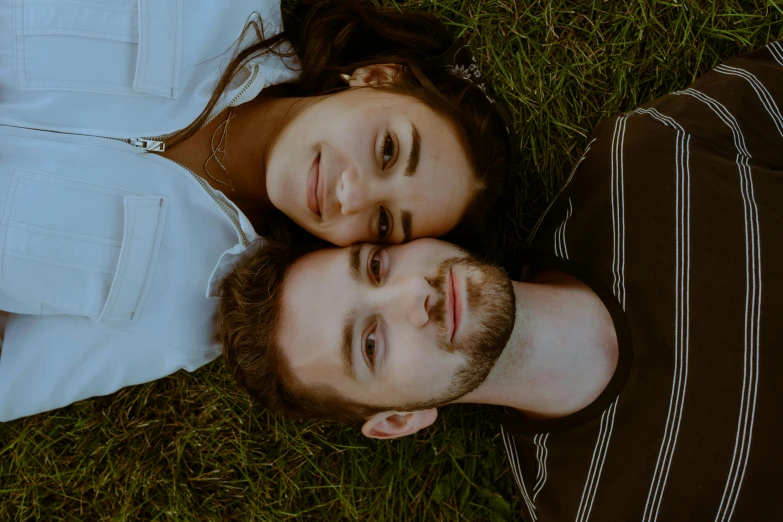 two young people lying down together in the grass