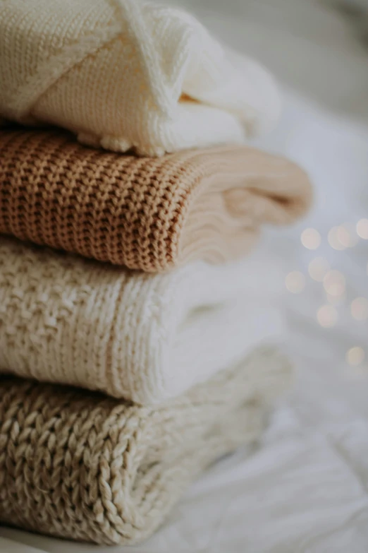 blankets are stacked up on a white bed