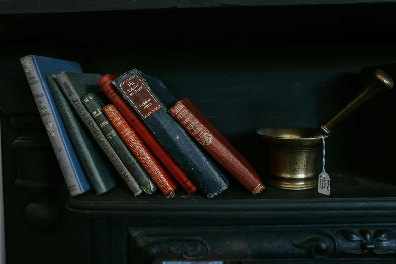 some books on top of a shelf with a gold cup and a hammer