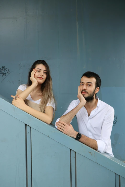 a young man and woman sitting next to each other in a tennis cage