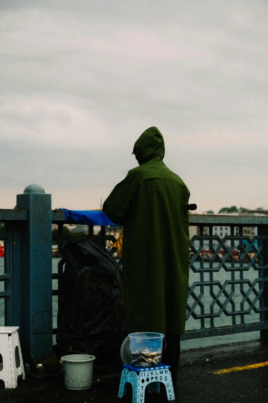 the man is standing next to the bench wearing a hood