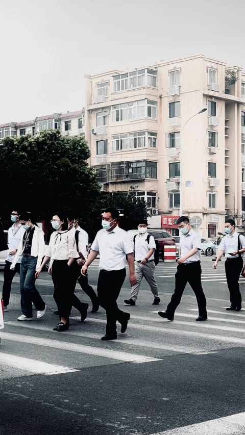 people in masks cross the street in a cross walk