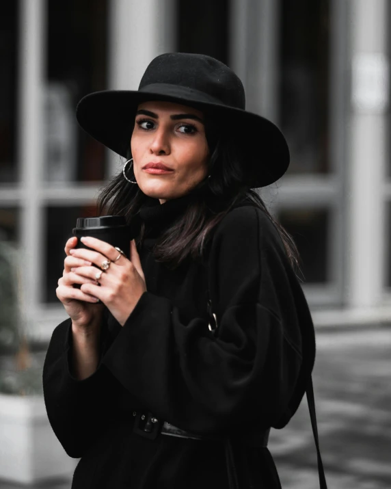 woman dressed in black outfit holding a cup