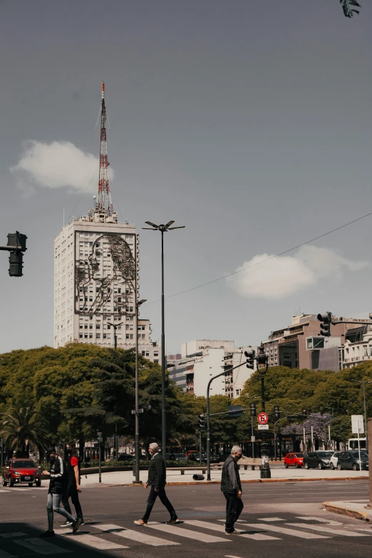 pedestrians walk on a crosswalk in the city with tall buildings