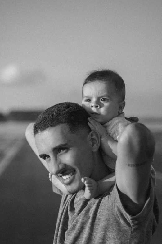 a man holding up a baby boy with his face to his ear