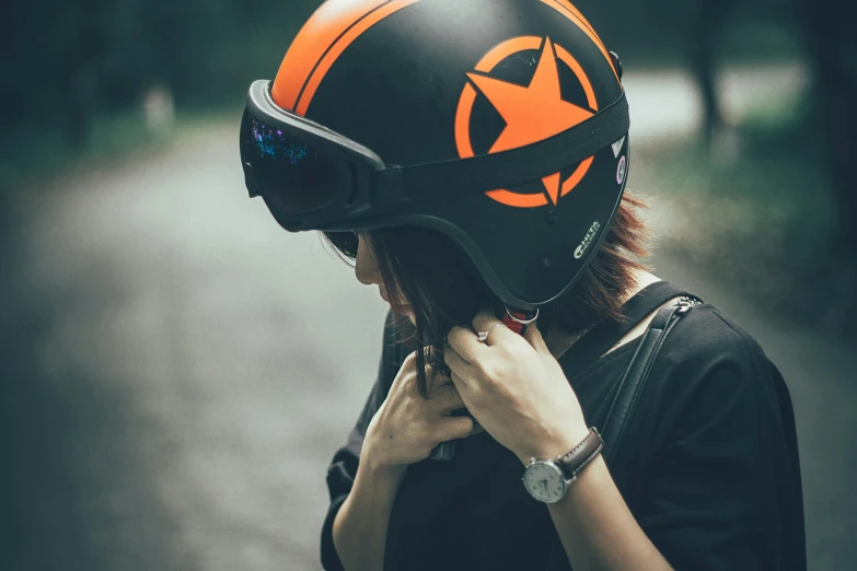 a woman is rubbing her face with an orange star helmet on