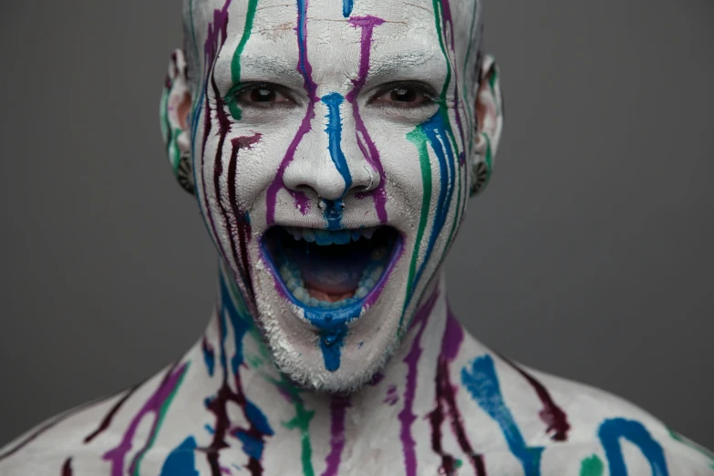 a man with white and purple makeup has smeared his face