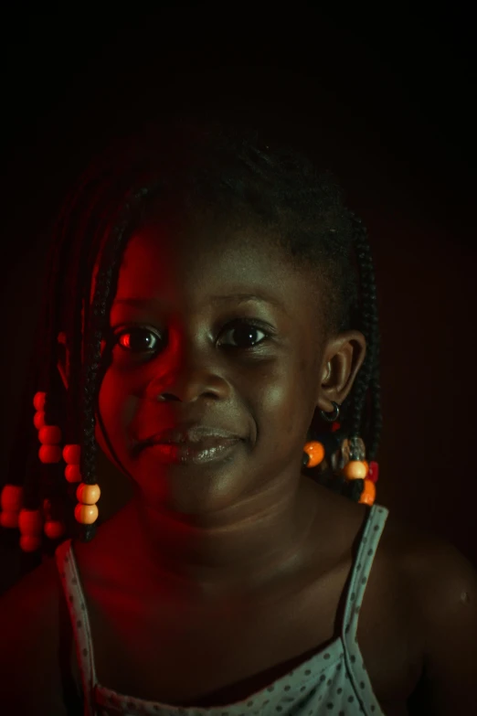 a  wearing bright orange beads standing in a black room