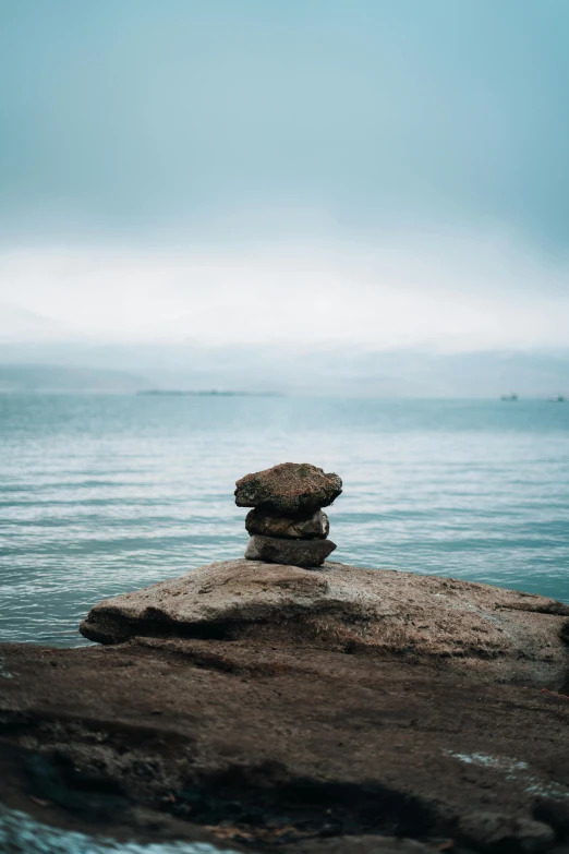 a stack of rocks by the ocean with water in the background