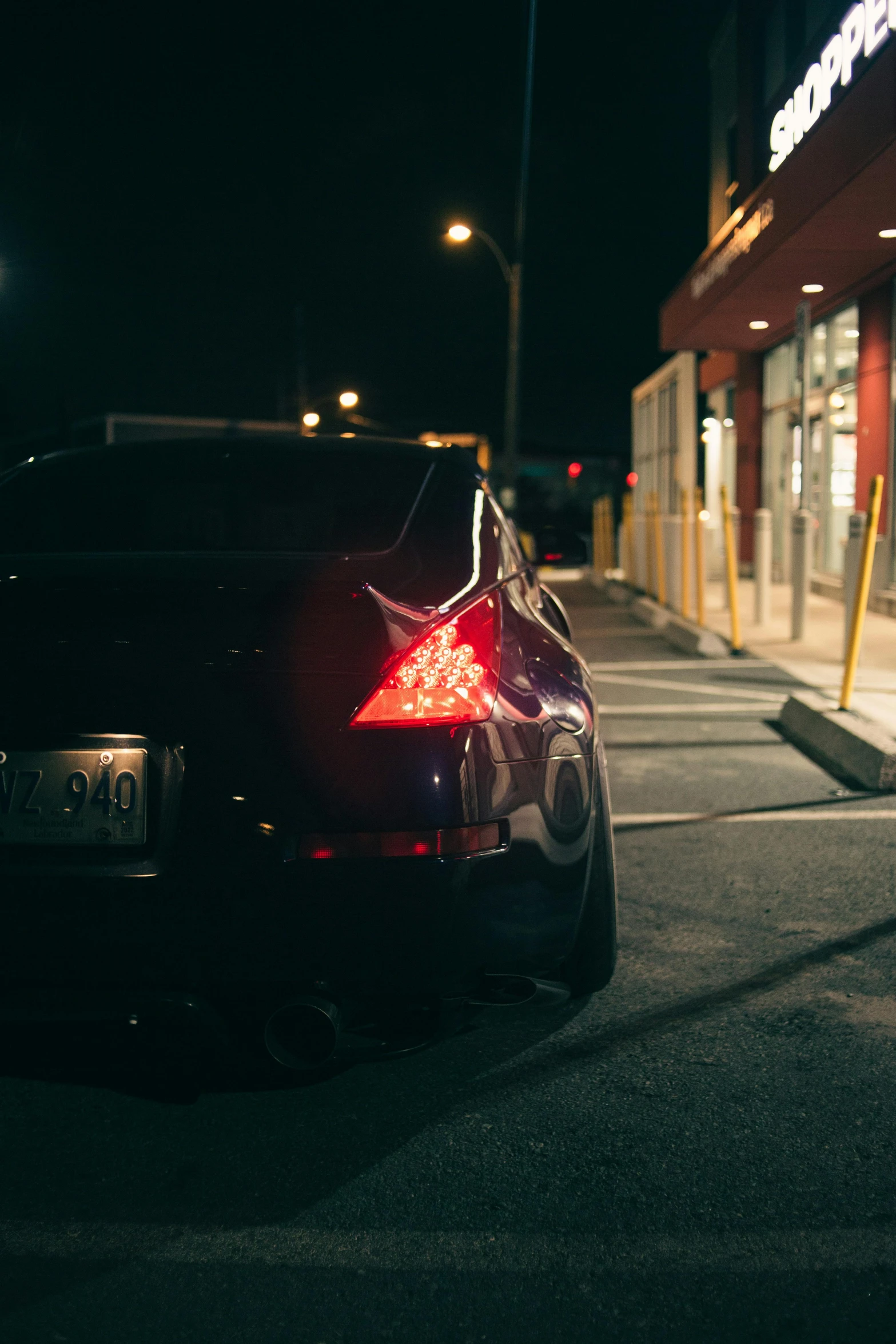 a dark street with a black car parked outside