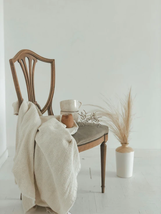 a white chair and table with two vases sitting on top of it