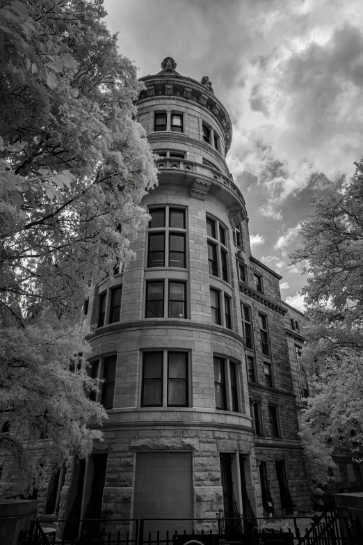 a tall brick building with iron gates near trees