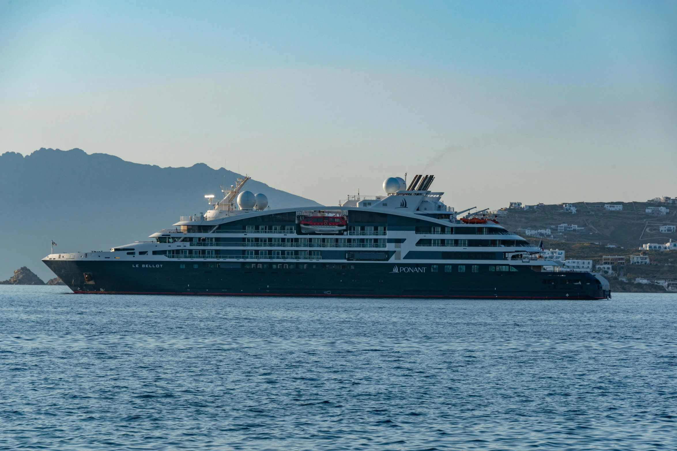 a cruise ship sailing across the ocean in front of mountains