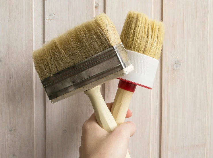 a person holding two wooden brushes up to each other