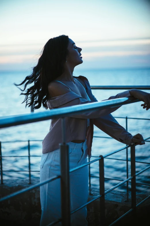 a young woman standing on the deck of a ship at dusk