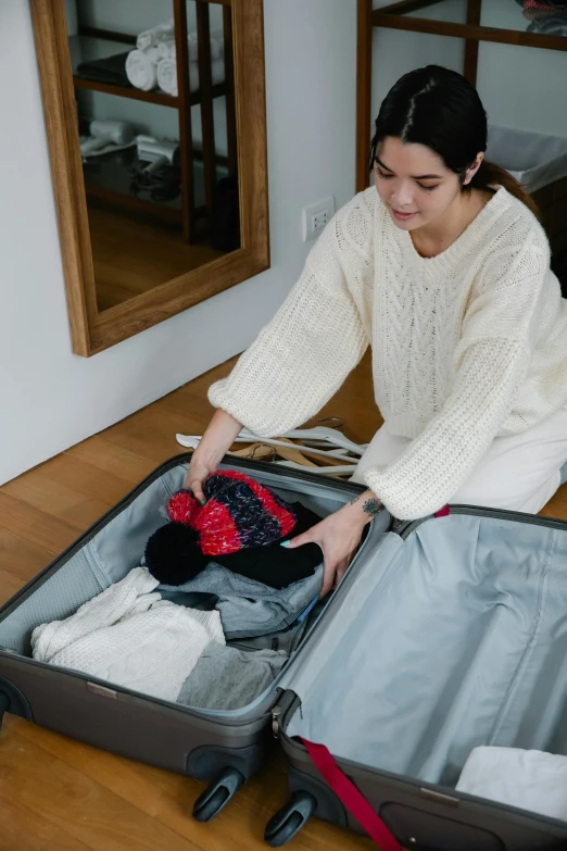 a woman kneeling down looking inside an open suitcase