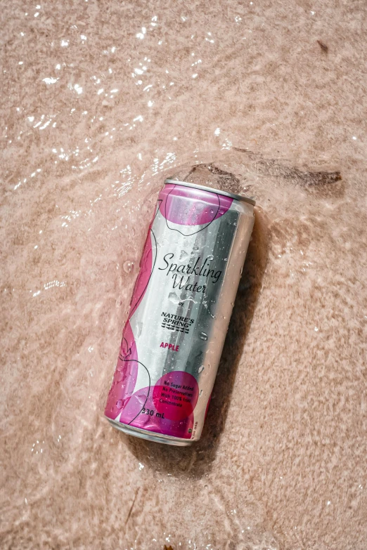 a can of soda floating on the sand near the ocean