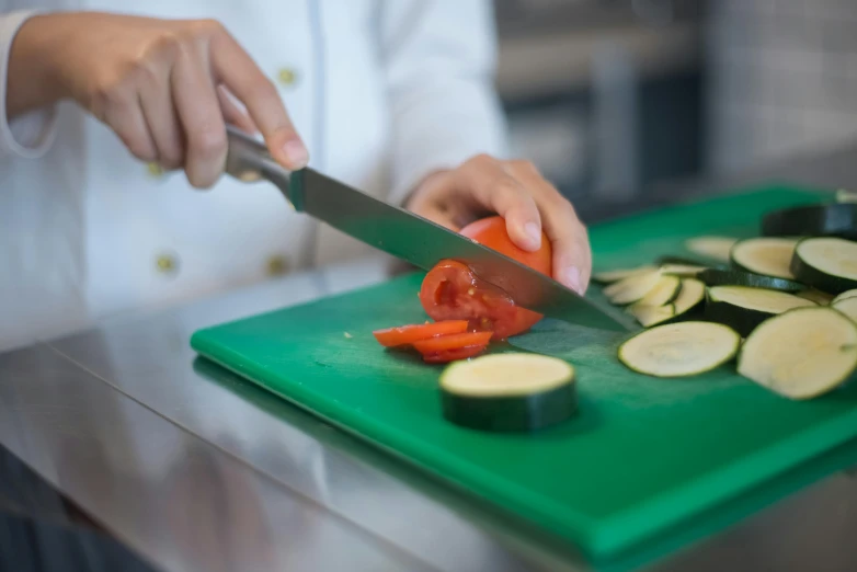 a person  up vegetables on a  board