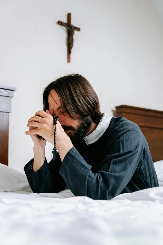 a man is sitting on a bed and looking into the distance