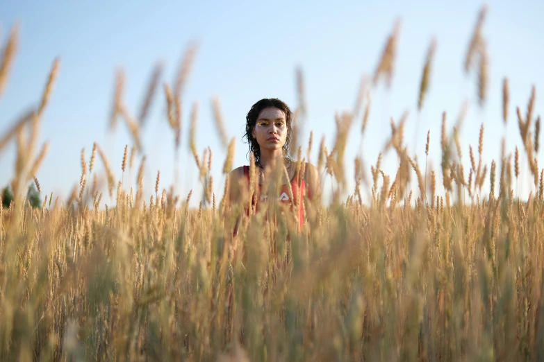 a woman is standing in tall grass and looking into the distance